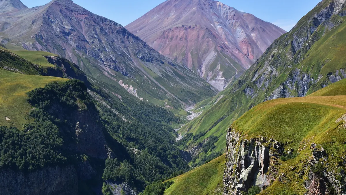 A green valley cutting through the rugged Caucasus mountains in Georgia