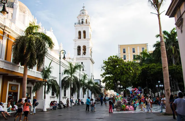A palm-lined plaza in front of the white cathedral bell tower in Veracruz, Mexico