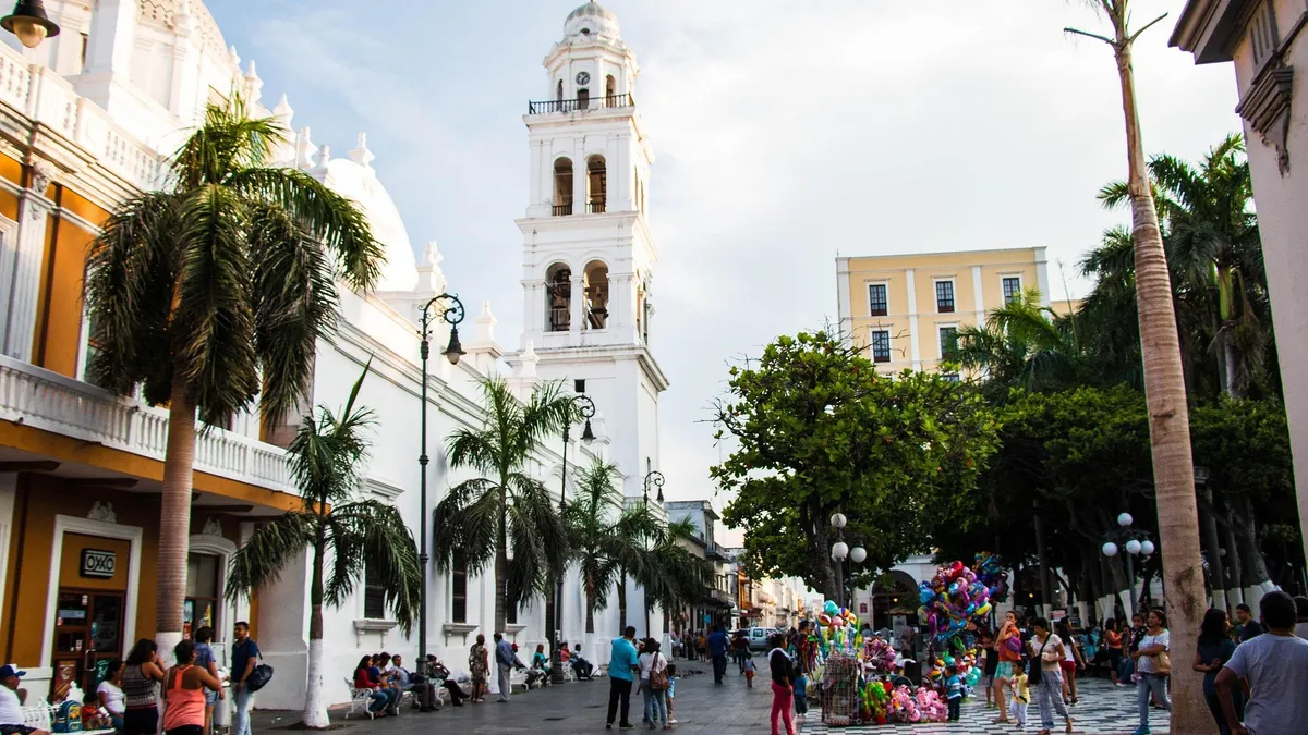 A palm-lined plaza in front of the white cathedral bell tower in Veracruz, Mexico